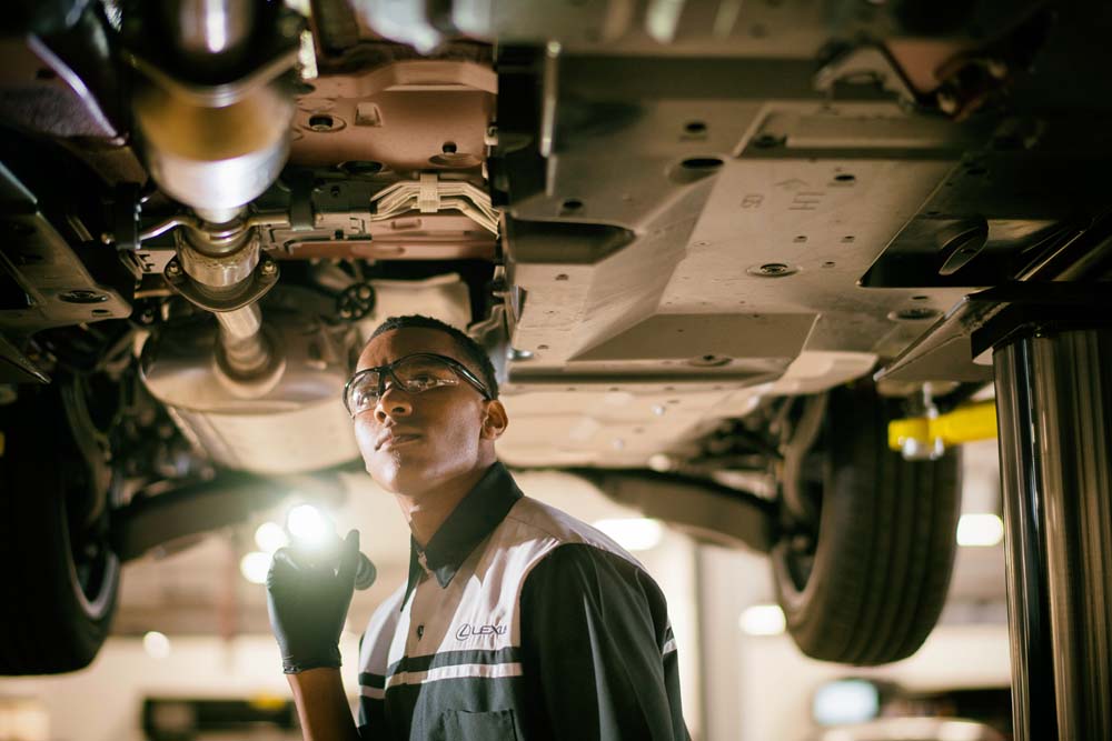 Lexus technician inspecting a hybrid battery under the vehicle